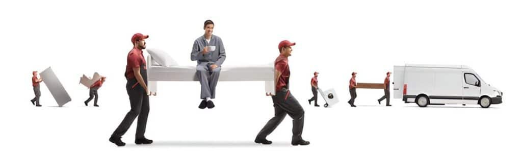 Two cheerful local movers in red caps and uniforms carefully carry a bed with a man sitting comfortably on top, sipping from a mug. Other movers transport boxes and appliances nearby, all heading towards a white moving van. This depicts a seamless and efficient moving process.