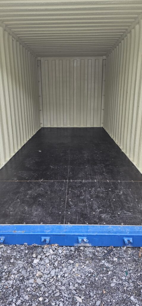 Inside of an empty shipping container with a dark wooden floor and ribbed, pale yellow walls, ready for moving from Dublin to Sligo.
