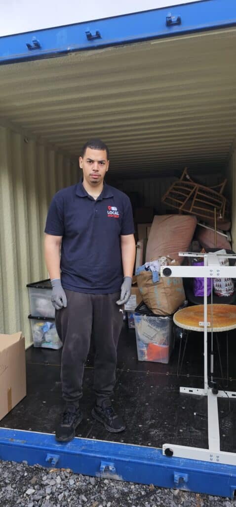 Man in 'Local Movers' shirt standing in a packed storage container, ready for a move from Dublin to Sligo.