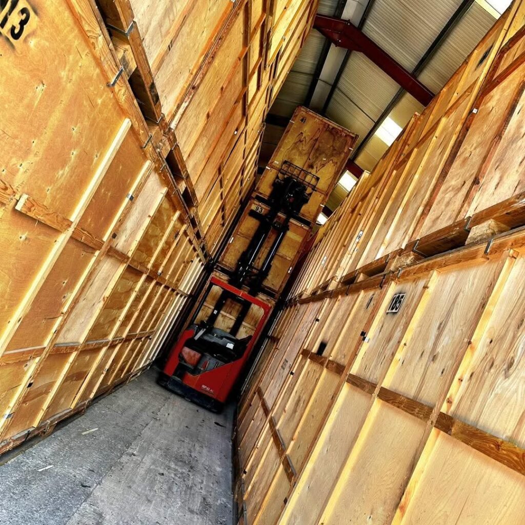 Red forklift moving wooden storage crates in a warehouse, possibly related to moving from Dublin to Sligo.