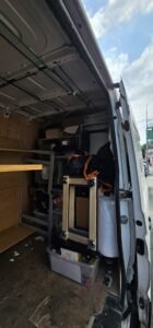 Interior of a white moving van packed with office furniture, boxes, and bubble wrap, ready for commercial relocation.