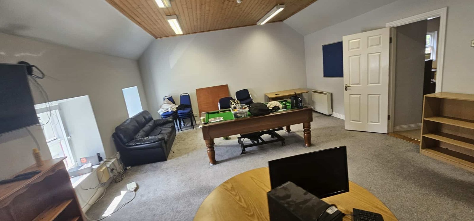 An empty office space with office furniture, including a desk, chairs, and a sofa, ready for commercial relocation by professional office movers.