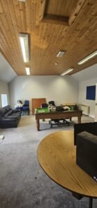 Empty office space with a pool table, couch, and desks, showcasing a commercial relocation by office movers.